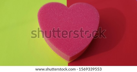 Pink-yellow sponge in the shape of a heart on yellow-pink paper (foreshortening, abstraction)