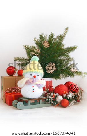 Cute knitted snowman, christmas tree, gift box and festive winter decorations. Christmas and New Year holidays background.