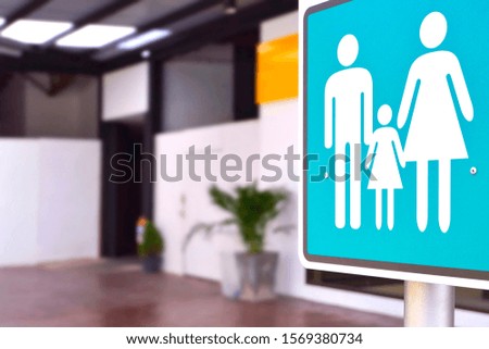 Focus at family restroom sign on metal pole with blurred background of outdoor bathroom in public area, close up with copy space