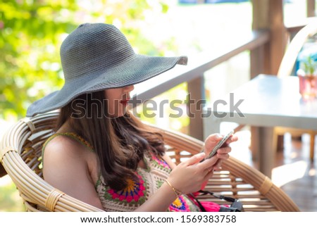 Happy woman wearing a hat sitting and using smart phoned(Happy Concept)