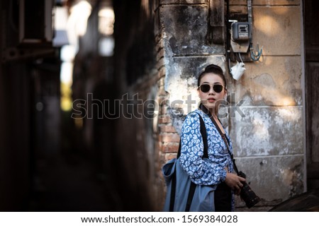 Happy woman wearing a sunglasses and holding camera with lovey light and shadow, (toned image), (blurry image),  (soft focus)