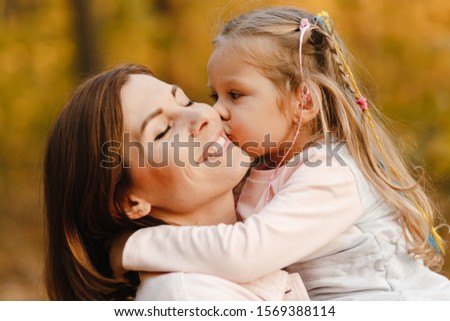Portrait of the little girl kissing her smiling happy mother