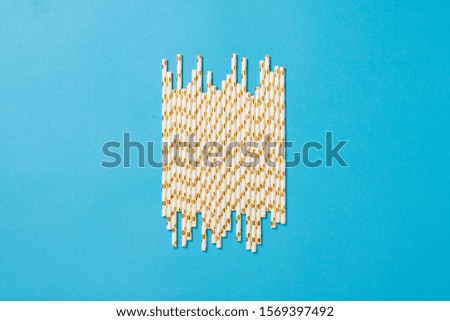 Festive white with gold drinking straws on a blue background. Holiday concept, decoration. Flat lay, top view