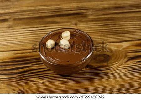 Glass bowl with delicious chocolate hazelnut spread on wooden table