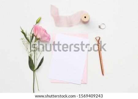 Flat lay shot of letter and eco paper envelope on white background. Wedding invitation cards or love letter with pink roses. Valentine's day or other holiday concept, top view, flat lay, overhead view