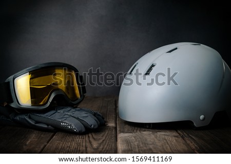 Ski helmet, ski goggles and gloves on a wooden background. The concept of skiing, proper clothing and preparation for winter sports.