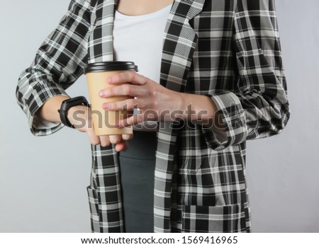 A business woman in formal clothes looks at her watch and holds a cup of coffee on a white background. Office worker, crop photo