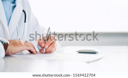 Close up of doctor signing prescription for patient