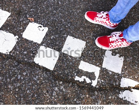 Red checkered shoes on checkered asphalt