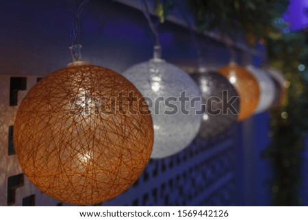 christmas glowing garland from orange, grey, white baubles in dark. Decoration ornament. Indoor. Blue light.