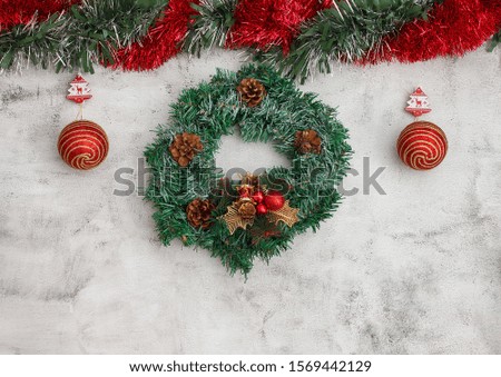 Christmas wreath on grey background with big red baubles. Red and green tinsel top. Space for text