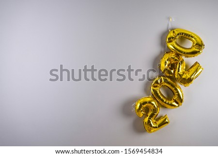 Celebrating the New Year 2020. Gold foil balloons 2020 on a gray background. Foil balls, festive concept for winter holidays.