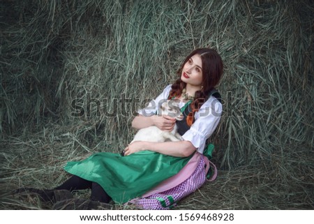 Beauty young girl outdoors enjoying nature.Funny picture a beautiful young women farmer with white goat.Summer mood.