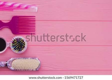 Colorful hair brushes on pink background. Colored hair brushes and combs. Space for text.