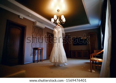 wedding dress hanging on a chandelier in a hotel room, wedding day, beautiful, modern dress, holiday atmosphere