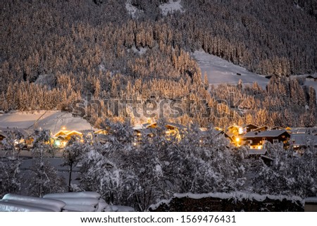 Winter night landscape with a view of the Austrian Tyrolean town of Neustift, in the background of fir trees in the snow
