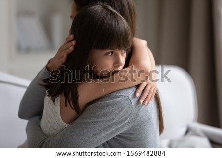Close up view of upset little daughter cuddling mother, child receiving protection and support from mommy, adopted kid girl and new parent, sole custody, offspring and motherhood connection concept Royalty-Free Stock Photo #1569482884