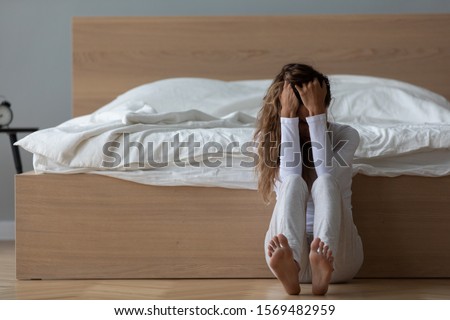 In the morning desperate woman sit on floor leaned on bed in bedroom cover face with hands crying suffers from loss or death of loved one, break up with boyfriend, goes through divorce restless night Royalty-Free Stock Photo #1569482959