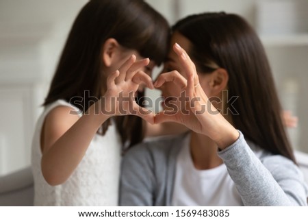 Close up focus of mum and kid girl fingers showing heart symbol, mother with little daughter touching with noses enjoy sweet moment of love tenderness. Children are life value, meaning of life concept Royalty-Free Stock Photo #1569483085