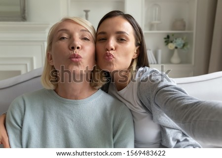 Blogger women use phone recording video vlog, faces of elderly mother and grown up daughter looking at camera blowing kisses make selfie webcam view, relative women family photography portrait concept