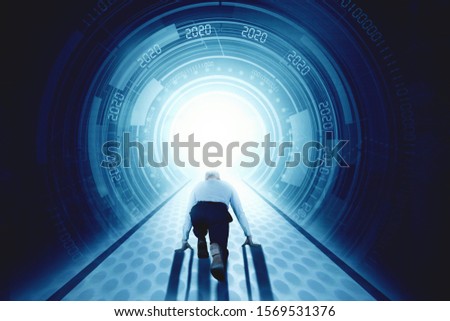 New Year 2020 business success concept: Back view of businessman in ready start running position in front of futuristic tunnel with number 2020 Royalty-Free Stock Photo #1569531376