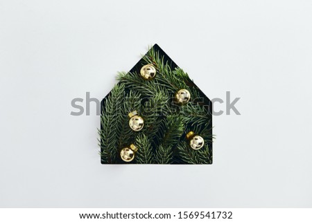 Christmas minimal concept - simple house silhouette made of christmas tree branch with yellow bauble. Flat lat, top view. Tree pine house in abstract style on white background. Christmas background.