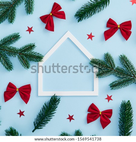 Christmas minimal concept - Christmas tree branch, confetti star and red bow decoration on blue background. Square mock up. White paper house frame, flat lay. Hipster winter greeting card.