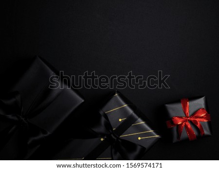 Top view of black gift box with red and black ribbons isolated on black background. Shopping concept boxing day and black Friday sale composition.