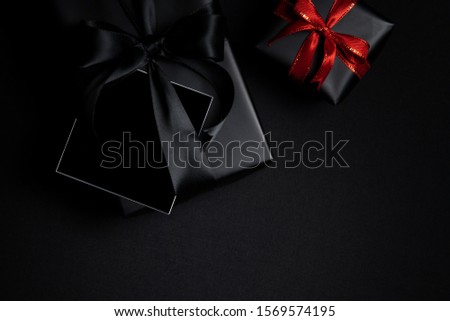 Top view of free space card for text with black gift box isolated on black background. Shopping concept boxing day and black Friday composition.