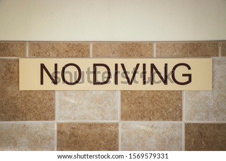No Diving sign poolside on wall