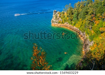 A ferry boat next to Miners Castle carrying tourists passes Miners Castle at Pictured Rocks National Lakeshore on Lake Superior
