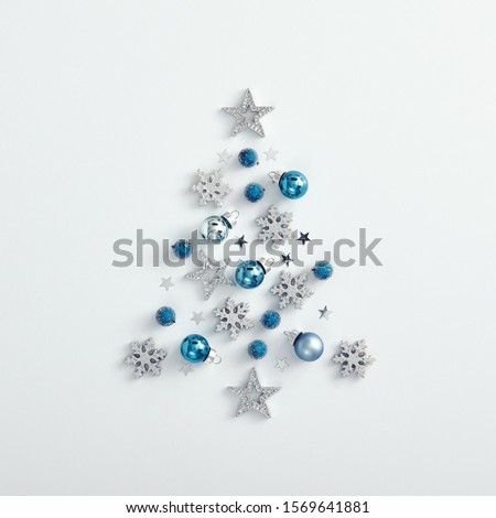 Christmas minimalist mockup - shape of xmas tree from blue bauble, silver snowflake and star on white background. Square layout, flat lay, top view. Happy new year and merry christmas.