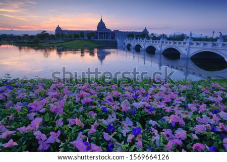 Spring Morning Twilight Scenery of Olympus Bridge and Chimeimuseum architecture reflected in pond & Sunrise & Pink poui petals fall is traditional French Romanticism style. Tainan, Taiwan. Asia.