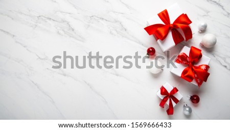 Merry Christmas and Happy Holidays greeting card, frame, banner. New Year. Noel. Christmas gifts and red decor on white marble background top view. Winter xmas holiday theme. Flat lay
