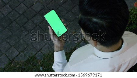 asian young businessman use 5g full display smartphone with green screen on the street