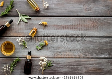 Essential oils and fresh herbs on dark wooden background top view pattern frame copy space