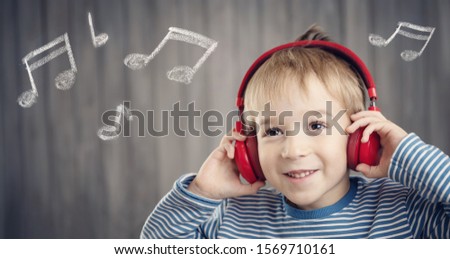little boy on wooden background with red headphones