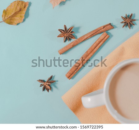 Autumn composition. Cup of coffee, autumn leaves , cinnamon sticks and anise stars on Bright Blue pastel  background. Flat lay, top view copy space.