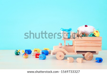 religion image of jewish holiday Hanukkah with spinning top and doughnut over wooden car toy and pastel blue background