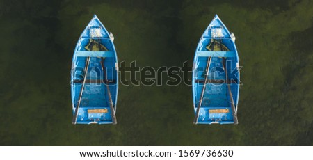 Top down aerial view of two blue rowing boats on a water background