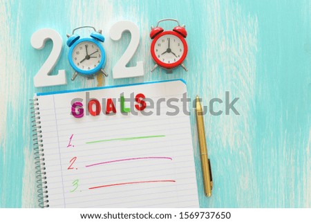 Business concept of top view 2020 goals list with notebook over wooden desk