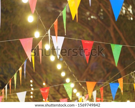 Outdoor decoration. colorful festive flag and light bulb hang with cross line at outdoor holiday market.