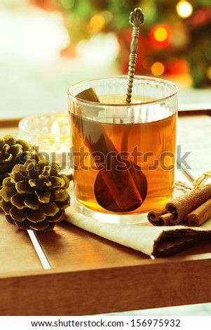 Hot Christmas drink on wooden tray over Christmas tree bokeh background