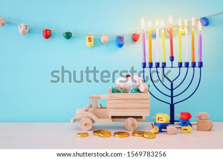 religion image of jewish holiday Hanukkah with menorah (traditional candelabra), spinning top and doughnut over wooden toy car
