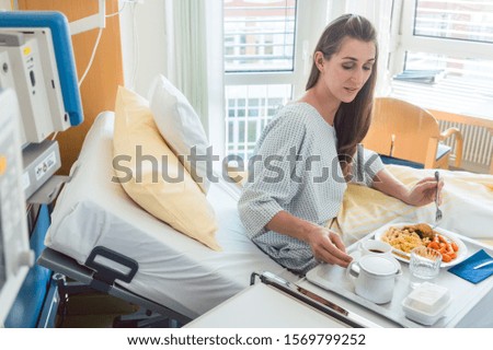 Patient in hospital lying in bed eating meal enjoying the food