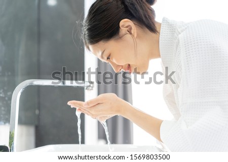 Young Asian Woman Washing Her Face In Bathroom.