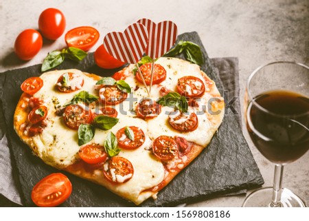 Heart pizza with mozzarella and tomatoes on a slate. Valentine's day date food concept.