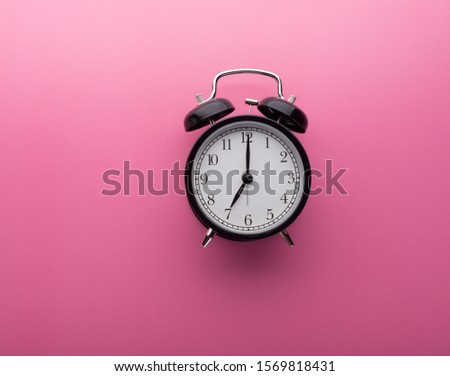 Alarm clock on pink background top view. Seven o'clock. Concept of time.