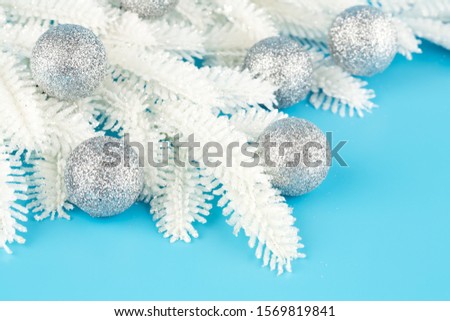 Christmas decoration with gray balls and fir-tree white branch on the blue background.