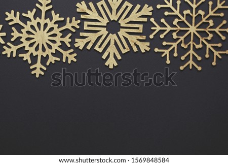 Winter holiday background.Black wallpaper with wooden rustic snowflakes in flat lay style.Handmade crafts for New Year and Christmas decoration.Poster with empty space for text,edited in fading film